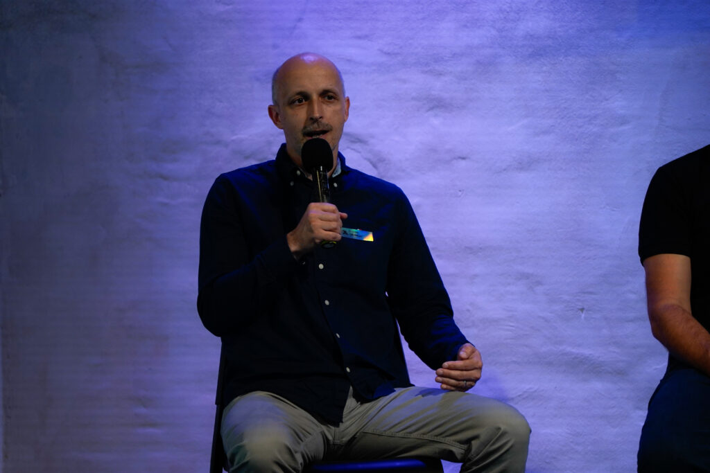 Michal Vanovčan zo Seedstartera sedí s mikrofónom na pódiu Startup Awards Slovensko a hovorí počas panelovej diskusie.